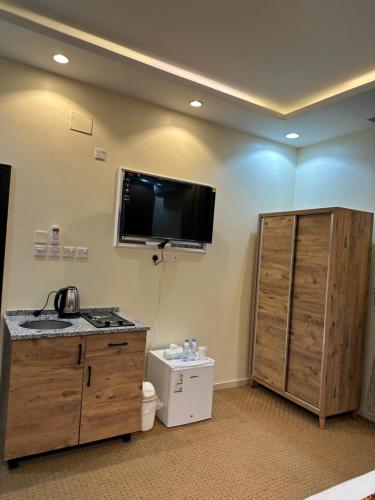 a room with a tv on the wall and a bathroom at فندق جارة الغيم للاجنحة الفندقية in Fayfāʼ