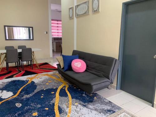 ein Wohnzimmer mit einem Sofa und einem rosa Kissen in der Unterkunft HOMESTAY HONEY PARIT BUNTAR in Parit Buntar