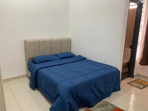 HOMESTAY HONEY PARIT BUNTAR في باريت بونتار: غرفة نوم مع سرير مع لحاف أزرق