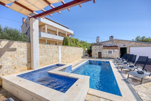 einen Pool mit Stühlen und ein Haus in der Unterkunft Coastal Paradise Villa with Pool - Happy Rentals in Sveti Filip i Jakov