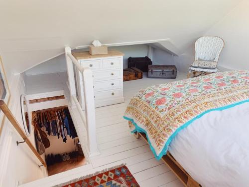 a bedroom with a bed and a dresser and chairs at Cottage On Windsor in Cape Town