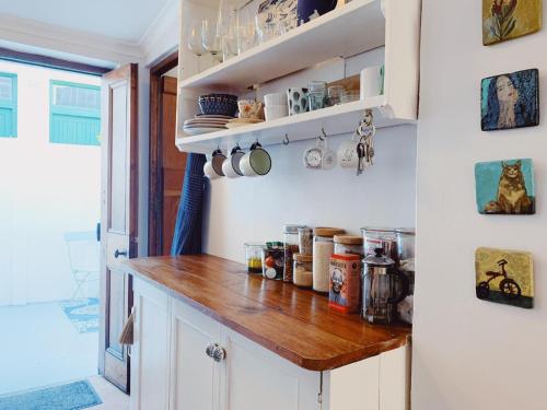 a kitchen with white cabinets and a wooden counter top at Cottage On Windsor in Cape Town