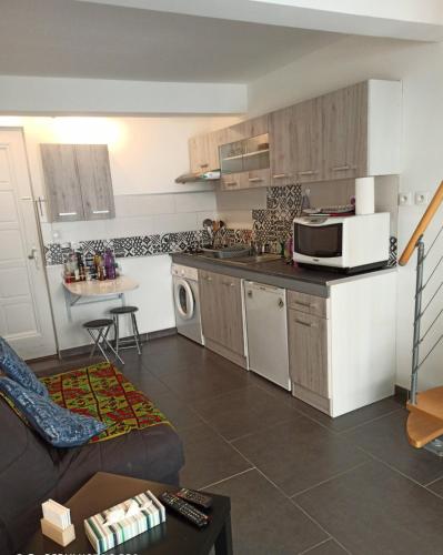 Il comprend une petite cuisine avec un canapé et un four micro-ondes. dans l'établissement Escale à Castelnaudary, à Castelnaudary