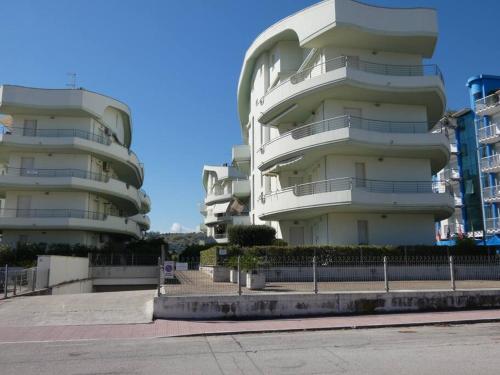 ein großes weißes Gebäude mit Balkonen neben einer Straße in der Unterkunft Appartamento Sirena in Tortoreto Lido