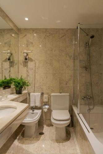 a bathroom with a toilet and a sink and a shower at Hotel Dom Carlos Park in Lisbon