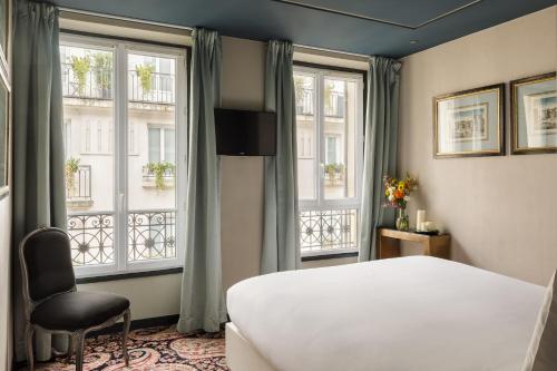 a bedroom with a white bed and two windows at Albert's Hotel in Paris