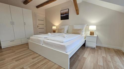 two beds in a bedroom with white walls and wood floors at YFB I 130m2 Designwohnung mit 2 Bädern in Gera