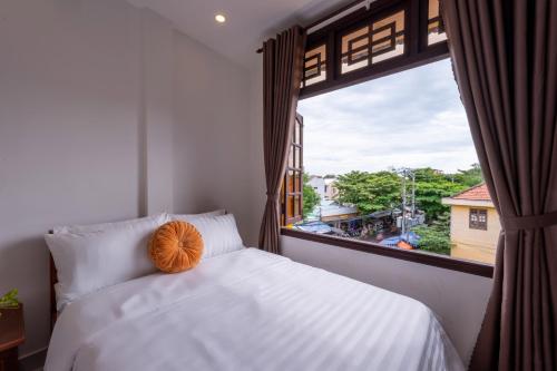 a bedroom with a bed and a large window at Golden Sun Hotel Hoi An in Hoi An