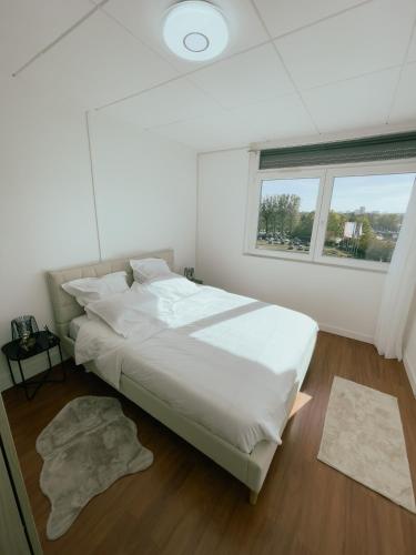 - une chambre avec un grand lit blanc et une fenêtre dans l'établissement Appartement Cosy & Connecté à 15 min de Paris, à Soisy-sous-Montmorency
