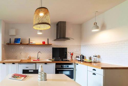 a kitchen with white cabinets and aendant light at Charmant appartement à Sigean - 23 m² - Climatisation in Sigean