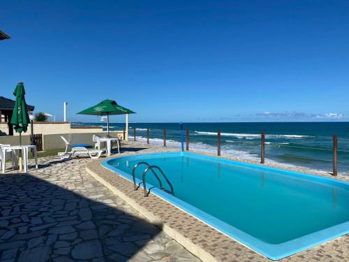 uma piscina com a praia ao fundo em Casa Conchas do Mar na Barra de São Miguel