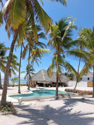 a resort swimming pool with palm trees on the beach at Anna's House with pool in Pingwe