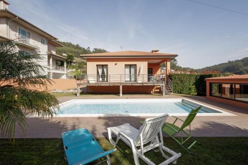 a swimming pool with two chairs and a house at Casa Azevedo in Vila Nova de Famalicão