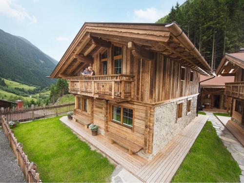 ノイシュティフト・イム・シュトゥーバイタールにあるGletscher-Chalet Stubaiの木造家屋のバルコニーに立つ夫婦