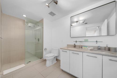 a white bathroom with a toilet and a shower at Spacious 3-Bedroom Midtown Condo in Miami