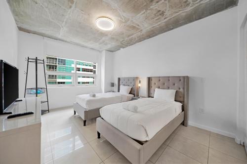 Duas camas num quarto branco com uma televisão em Spacious 3-Bedroom Midtown Condo em Miami