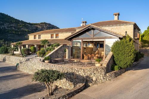 a large house with a stone wall and a house at Hotel Alahuar in Benimaurell