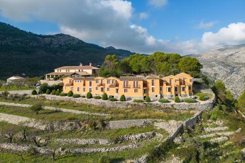 a large yellow house on a hill with trees at Hotel Alahuar in Benimaurell