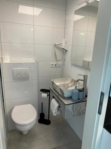 a white bathroom with a toilet and a mirror at Ferienwohnung am Freudenthal in Soltau