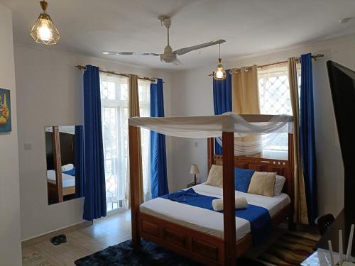 モンバサにあるAffordable neat studio furnished apartment in Mtwapaのベッドルーム(天蓋付きベッド、青いカーテン付)