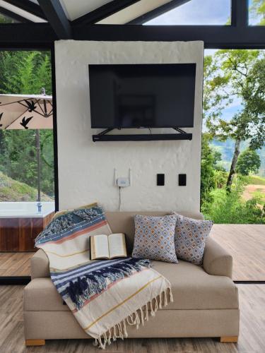a living room with a couch with a flat screen tv at Cabaña Bambú in Ciudad Bolívar