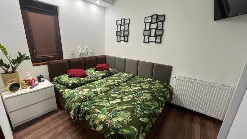 a bedroom with a bed with a green blanket and red pillows at Crooked stairs in Zielona Góra