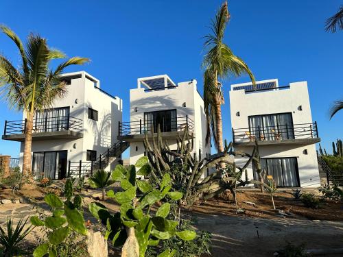 a white building with palm trees in front of it at Villas Del Scarlet Cardones in Pescadero