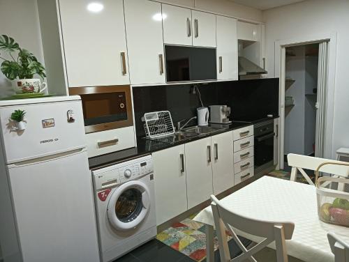 a kitchen with white cabinets and a washer and dryer at House da Didy in São João da Pesqueira