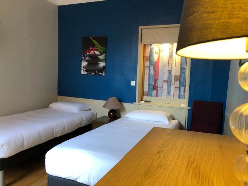 duas camas num quarto com paredes azuis e uma mesa em Villa Liberté em Villejuif