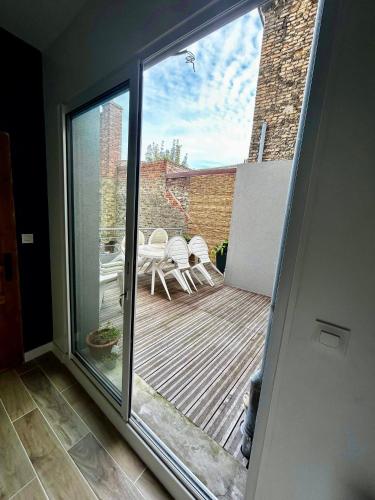 une porte coulissante en verre menant à une terrasse avec des chaises. dans l'établissement Maison hyper centre de dunkerque, à Dunkerque