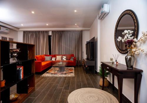 a living room with a red couch and a mirror at Manjaro Luxury Suites at Stella Place, East Legon in Accra