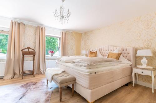 a white bedroom with a large bed and a chandelier at Waldhotel und Restaurant Zeitreise in Bramsche