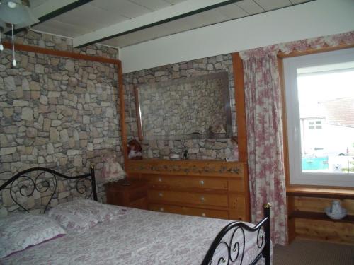 a bedroom with a bed and a stone wall at Chez Jean Marc et Corinne in Priay