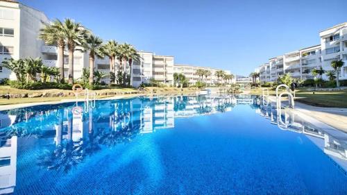 una grande piscina con palme e edifici di First Line Apartment in Puerto Banus a Marbella