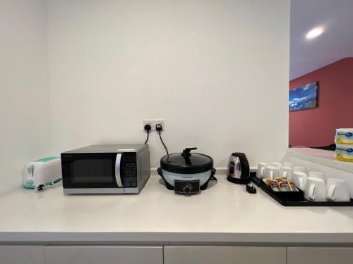 a kitchen counter with a microwave and a slow cooker at QUINCE HOME GRAND ION DELEMEN GENTING HIGHLANDs in Genting Highlands