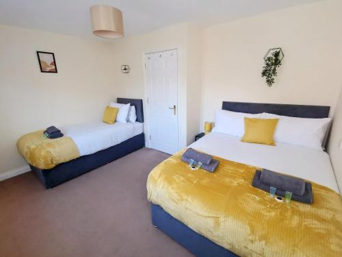 duas camas num quarto com branco e amarelo em No 23- Large Spacious 3 Bed Home - Parking & WiFi em Nantwich