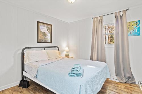 a white bedroom with a bed and a window at Beachy Getaway - Cozy and Secluded Lodge Home in Knightdale