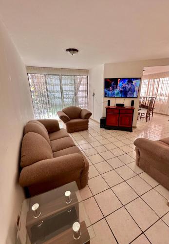 a living room with a couch and a flat screen tv at Casa Garcia-5 habitaciones, Auditorio GNP Estadios CC Parque Puebla in San Felipe Hueyotlipan