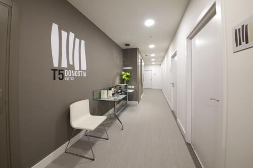 a corridor of a office with a white chair and a table at Pensión T5 Donostia Suites in San Sebastián
