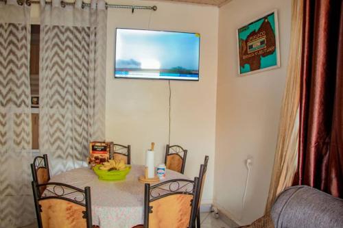 a dining room table with a television on the wall at Kigali bright housse in Kigali