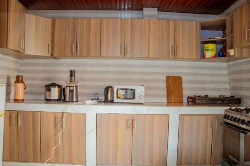 a kitchen with wooden cabinets and a microwave at Kigali bright housse in Kigali
