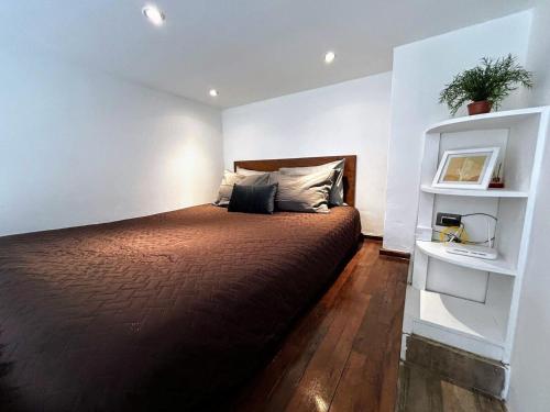 a bedroom with a bed and a white wall at Urban Shelter, El Dorm. in Guatemala