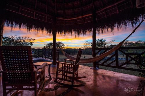 a hammock and chairs on a porch with a sunset at Hacienda Viva Sotuta de Peón in Tecoh