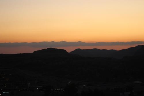 a sunset over the mountains and a body of water at H Luxury Hotel in Wadi Musa