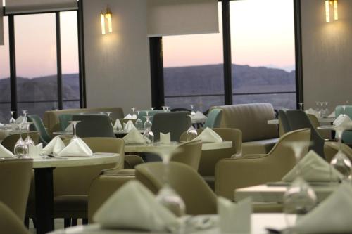 a dining room with tables and chairs and windows at H Luxury Hotel in Wadi Musa