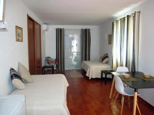 サレマにあるApartamentos Salema Praia Clubのベッド、デスク、テーブルが備わる客室です。