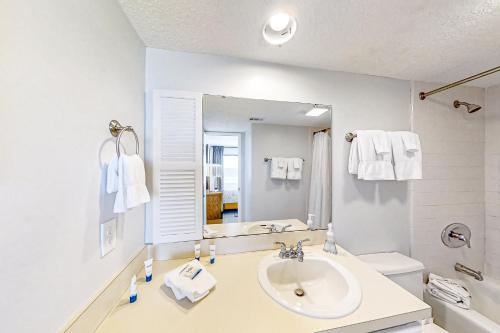 a white bathroom with a sink and a mirror at B175 Amelia Surf and Racquet in Fernandina Beach