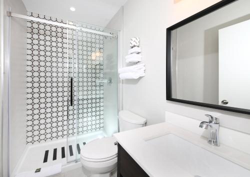 een witte badkamer met een douche en een toilet bij Cedar Lodge Motel in Goderich