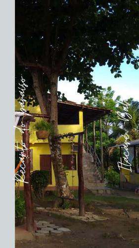 Una casa amarilla con un árbol delante. en Recanto do paraiso, en Itacaré