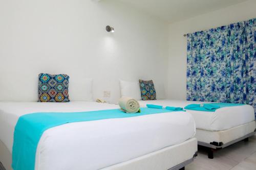 two beds in a room with blue and white at Hotel Maria de Lourdes in Cancún